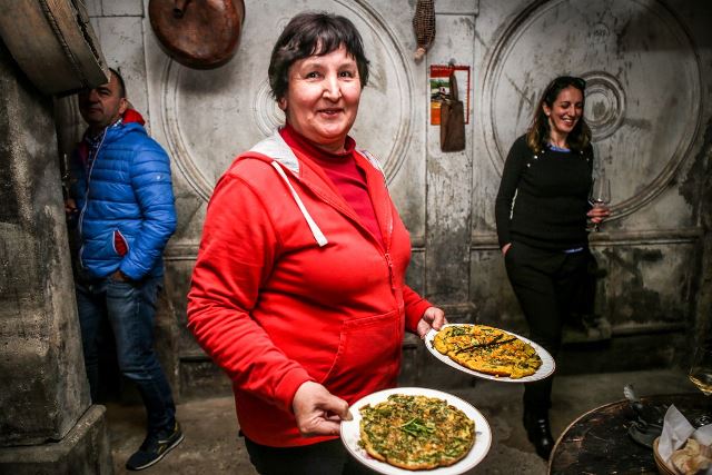 Slovenia: donna che porta due piatti in una cantina a gestione familiare