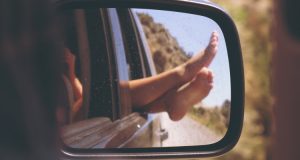 Piedi riflessi nello specchietto della macchina