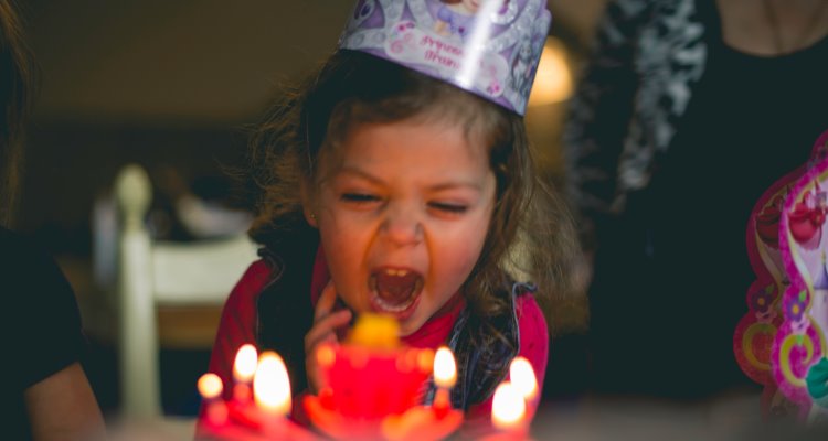 Bambina di fronte a una torta con le candeline