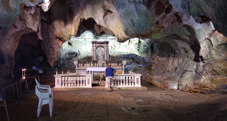 Grotte italiane: uomo che prega nella Grotta di San Michele, a Cagnano Varano