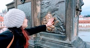 Ragazza che tocca altorilievo degli innamorati sul ponte Carlo di Praga