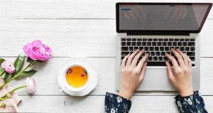 Aprire un blog: mani sulla tastiera di un pc, accanto a una tazza di tè
