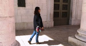 Social trekking: donna che cammina sotto ai portici di una città