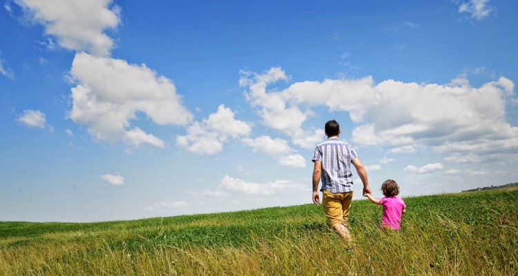 Val d'Orcia: padre e figlia di spalle che camminano sul prato