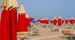 Sdraio e ombrelloni rossi e gialli su una spiaggia della Riviera Romagnola