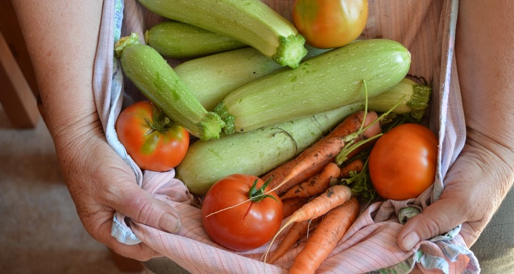 La cucina del sud di Creta: mani che tengono pomodori e zucchine