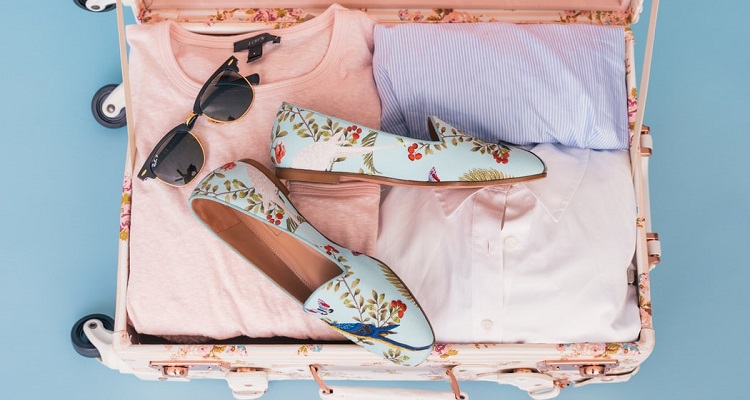 Cosa mettere in valigia: valigia rosa piena di oggetti femminili