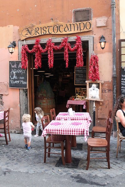 La mia Italia: tavolo con tovaglia a quadretti bianchi e rossi di fronte a una trattoria romana